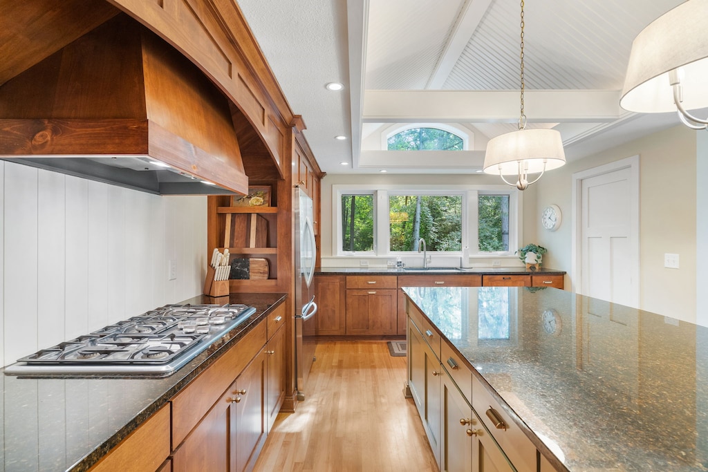 Your chef-ready kitchen features gleaming granite countertops, warm wood cabinetry, and garden views through expansive windows.