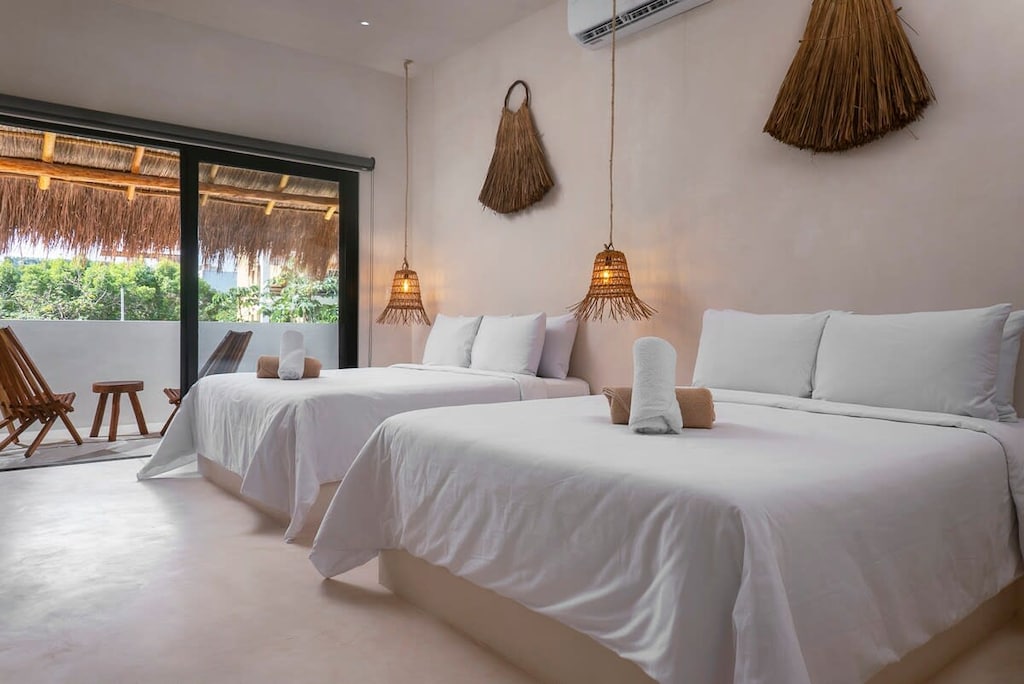 Spacious room with two beds. It has a private balcony with incredible views and a set of chairs.
