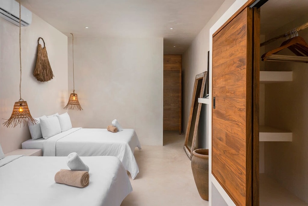 Spacious room with two beds. It has AC, closets, and a full-length mirror.