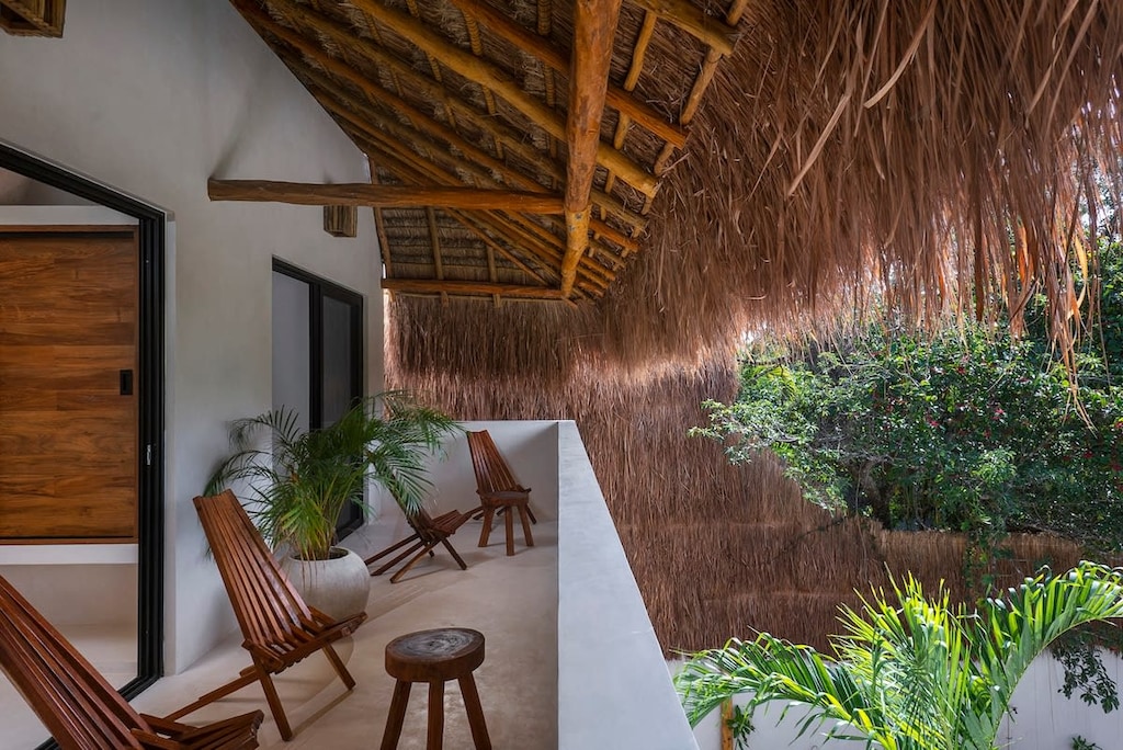 Private balcony shared by two second-floor rooms. They are covered by a typical palapa roof. Wooden chairs for enjoying the space.
