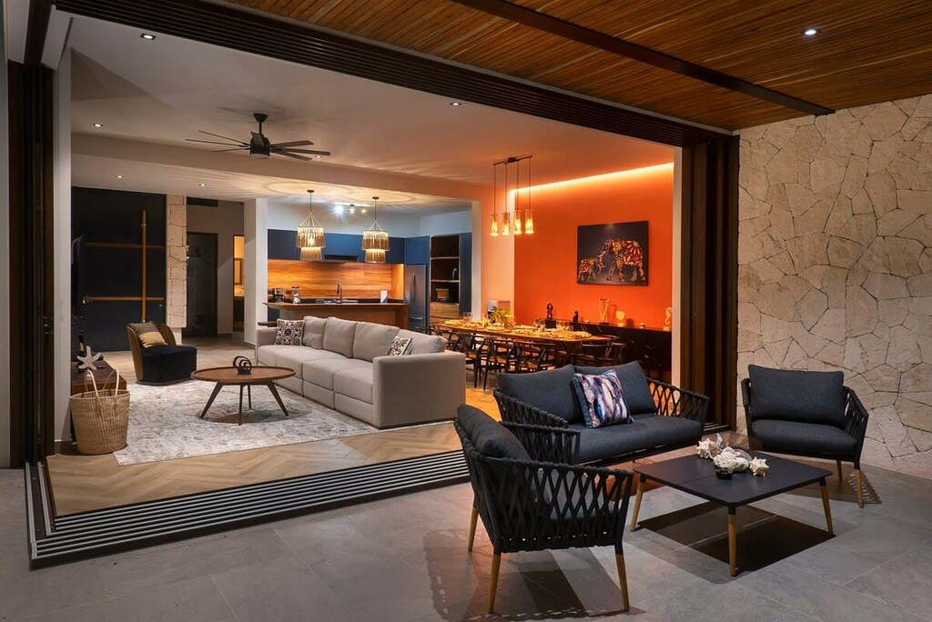 Ground floor of the villa, consisting of a kitchen, dining room, and living room. Outdoor patio with comfortable chairs.
