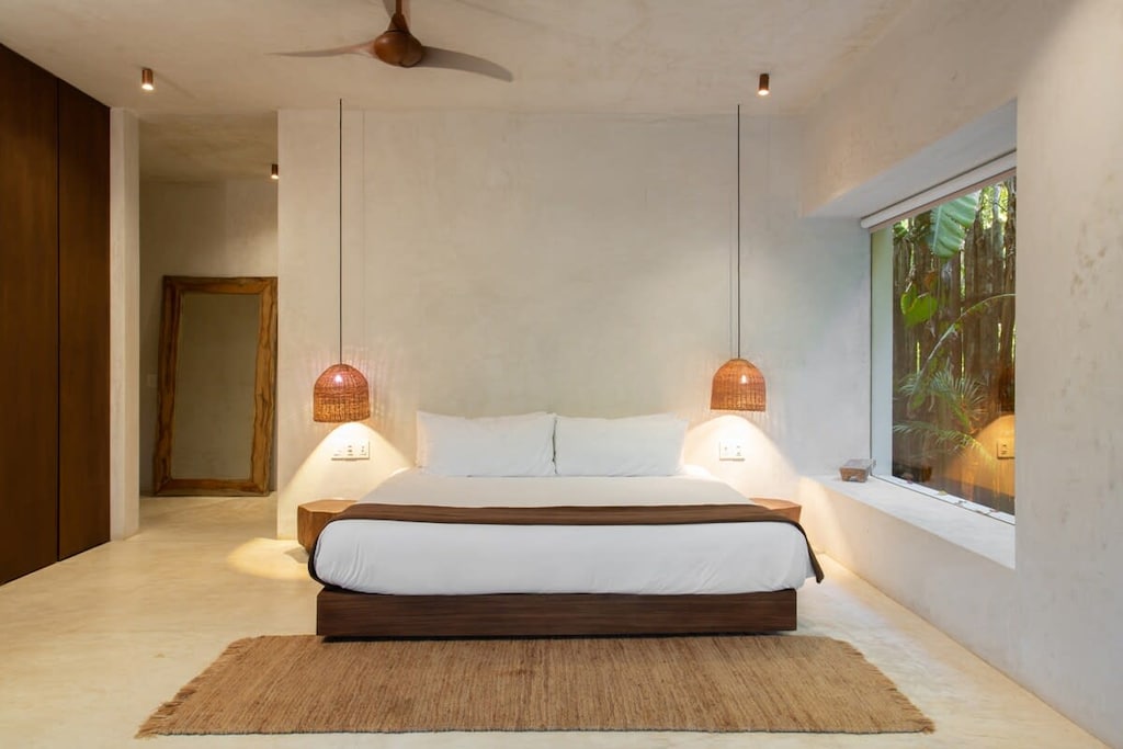 Minimalist and elegant room with a comfortable king-size bed. It has a ceiling fan, full-length mirror, and closets.
