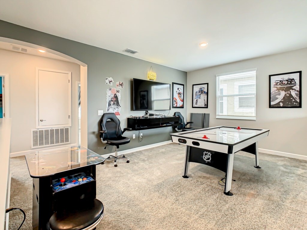 Entertainment-packed game room with air hockey, gaming setup, and comfy seating.