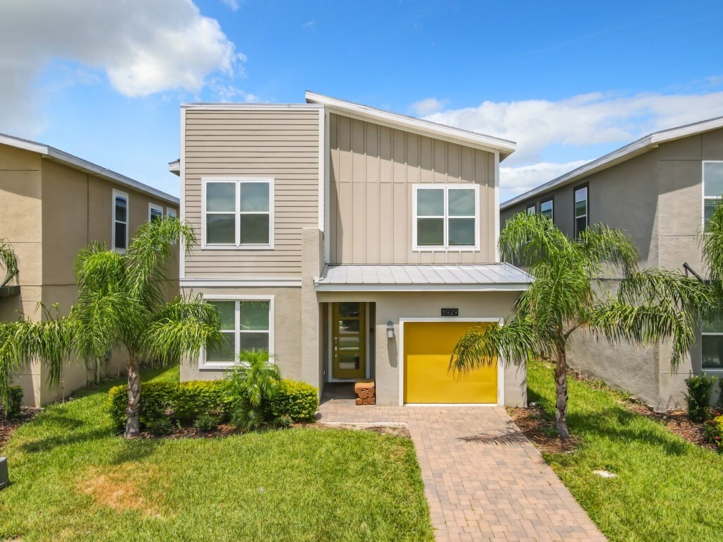 Charming modern exterior with a bright yellow door and lush landscaping.