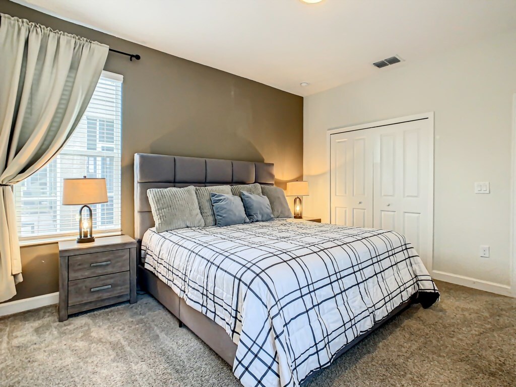 Comfortable bedroom with a stylish headboard, cozy bedding, and ample closet space.