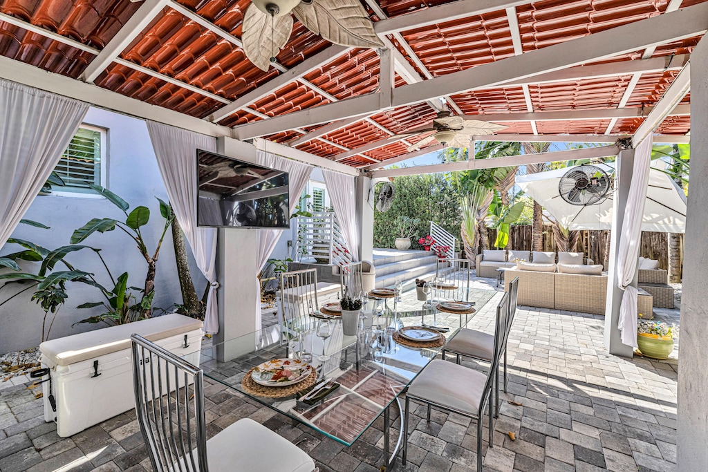 Private Backyard | Shaded escape featuring a covered gazebo with a dining table, ceiling fan, Smart Tv, and lounge seating.
