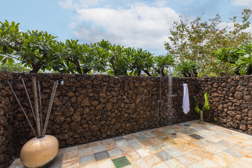 Private outdoor shower surrounded by lava rock—experience true Hawaiian indoor-outdoor living.