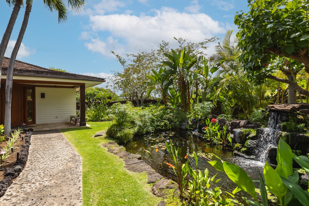 Tropical footpath alongside koi pond and gardens—tranquil island ambiance begins at the entrance.