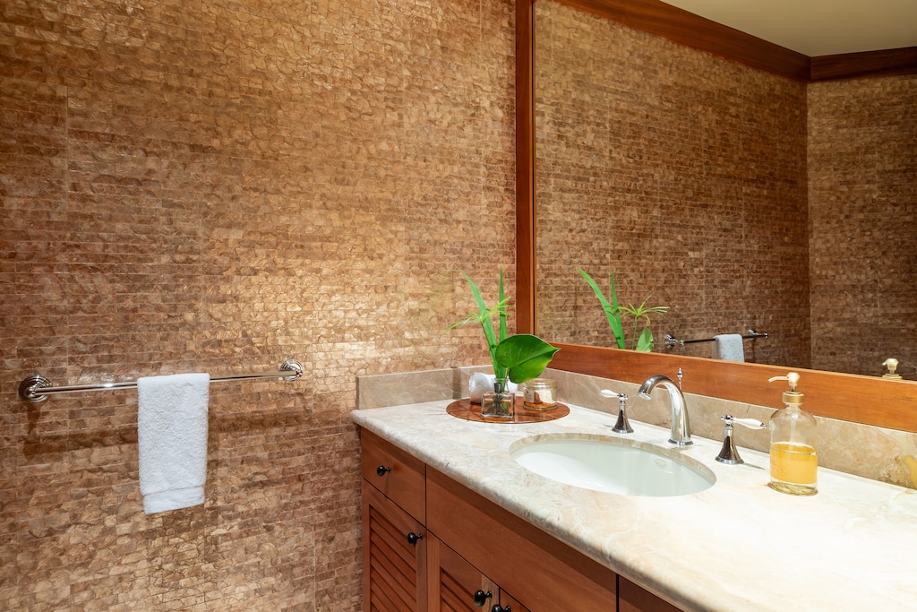 Powder room with tropical woven wall coverings and granite vanity—rich textures and island flair.