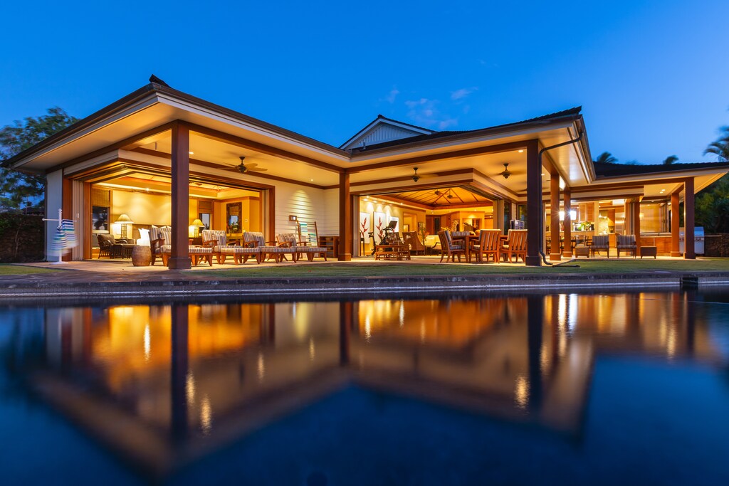 Twilight exterior of the estate home—private pool, glowing interiors, and open-concept elegance set the tone for your stay.