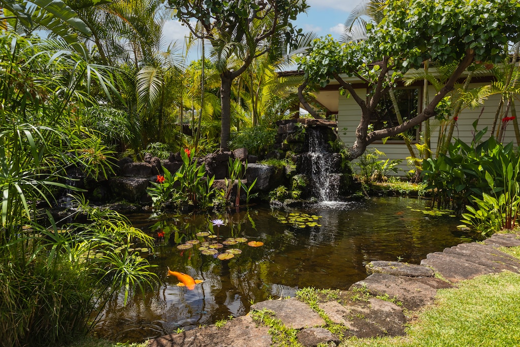 Tropical water feature nestled among mature landscaping—Hawaiian garden serenity at your doorstep.