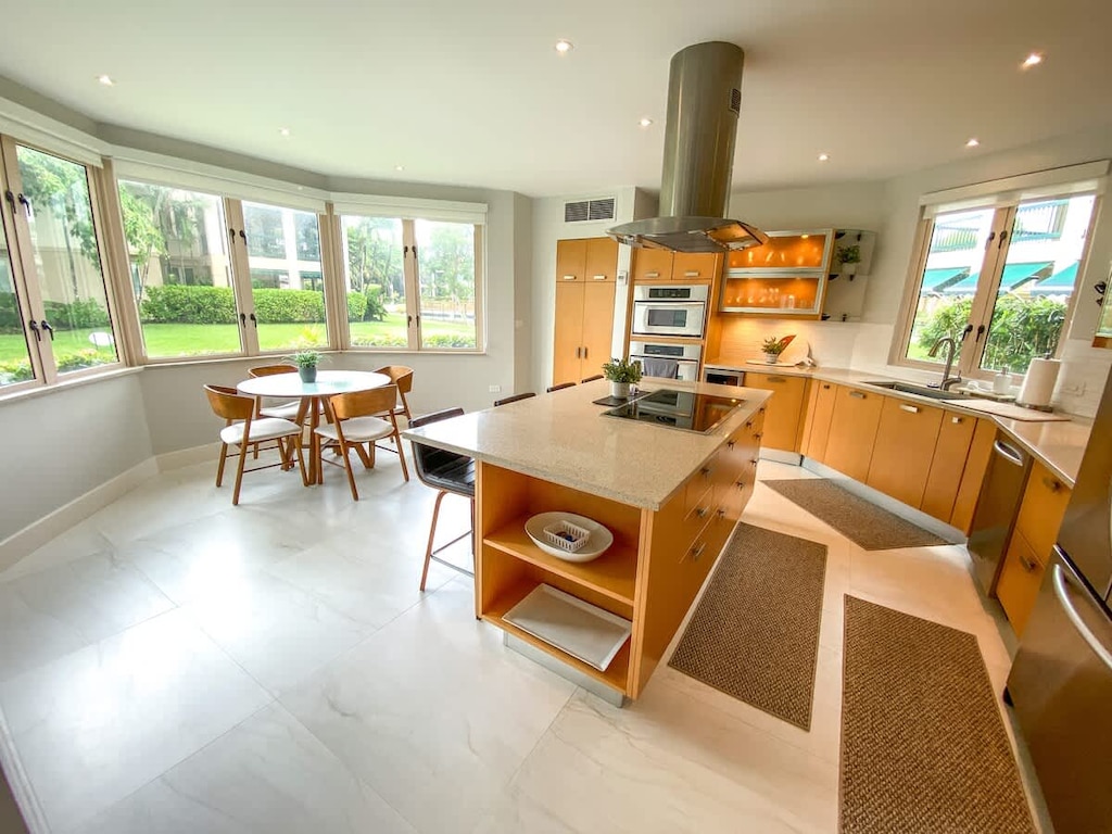 Vent hood extractor above the range
Triple-door refrigerator.
Breakfast nook, with panorama windows, overlooks landscaped gardens with a hint of ocean views; seats 4 on padded chairs around a circular dining table.
 