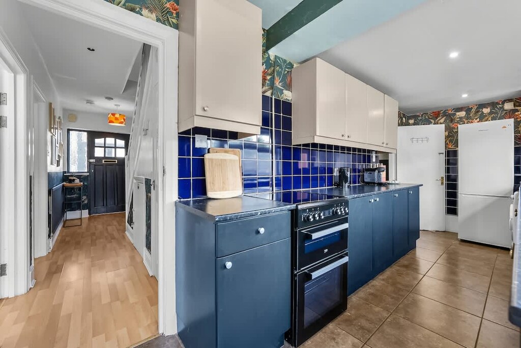 Cook in style in this vibrant kitchen, featuring bold blue cabinetry, modern appliances, and plenty of natural light. A perfect space for preparing delicious meals during your stay!