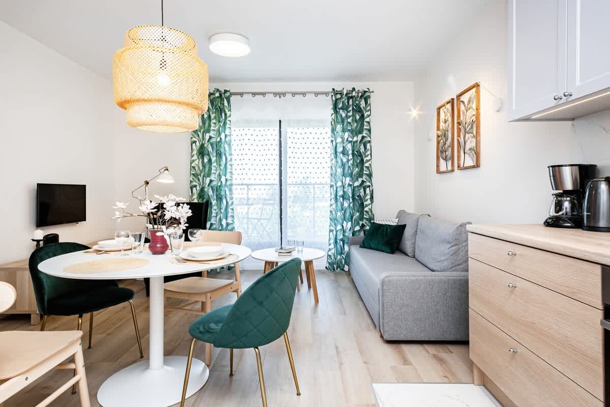 A living room showcasing a sofa, coffee table, and a large window for natural light. The open space feels airy and welcoming.