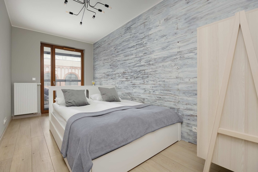 The bedroom, with soft lighting and a stone-textured wall, promotes calm and restful sleep.

