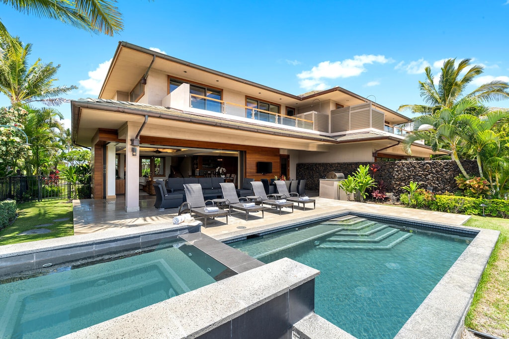 Tropical landscaping surrounds the pool and spa for serene outdoor living.