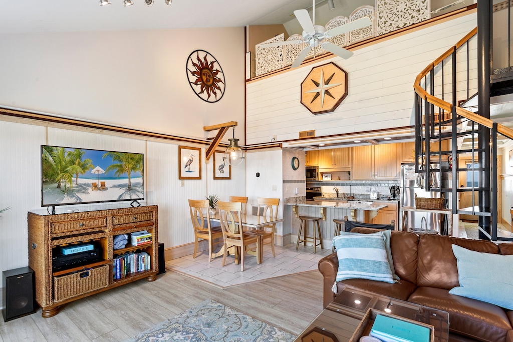 The open-concept Main Level boasts a cozy Living Area with high ceilings, a large Flat Screen TV, and a wall with windows and glass sliders overlooking the Pamlico Sound!