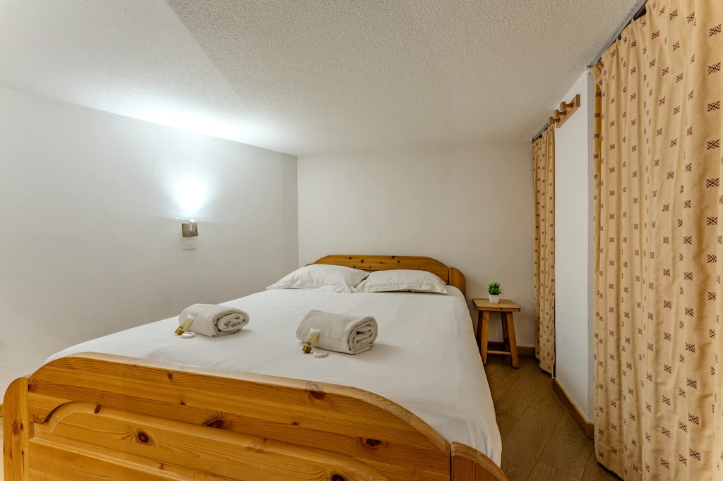 Comfortable sleeping area with quality linens and wooden finishes for a warm, chalet-style atmosphere.