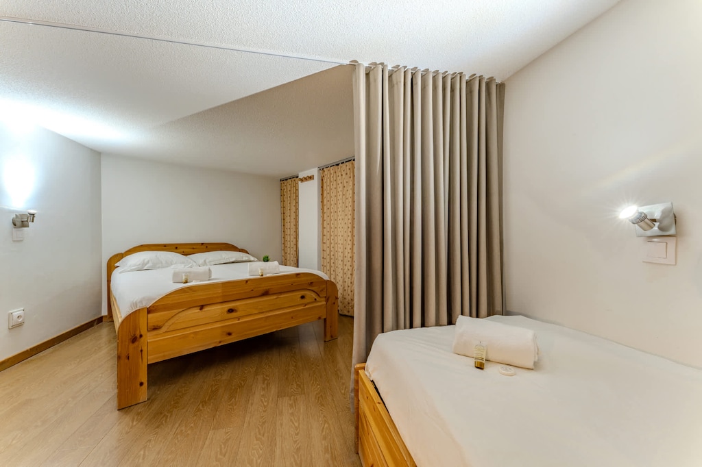 Spacious bedroom with a cozy double bed, soft lighting, and privacy curtain—perfect for restful alpine nights.