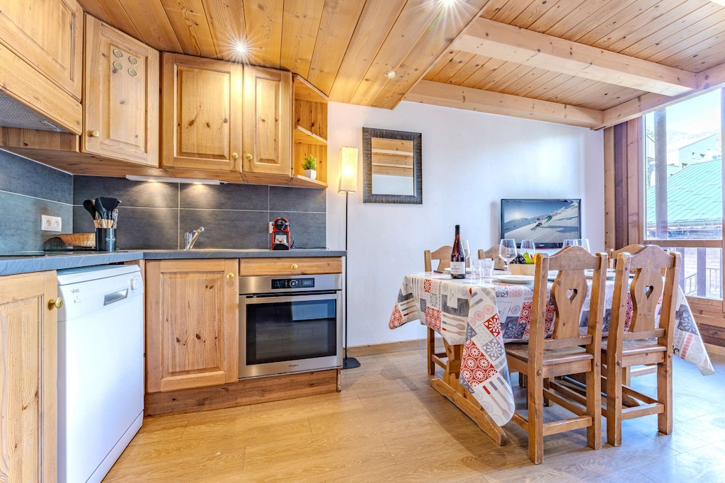 Open-plan living with wooden ceiling beams, dining table for 6, and fully equipped kitchen—ideal for shared meals and memories