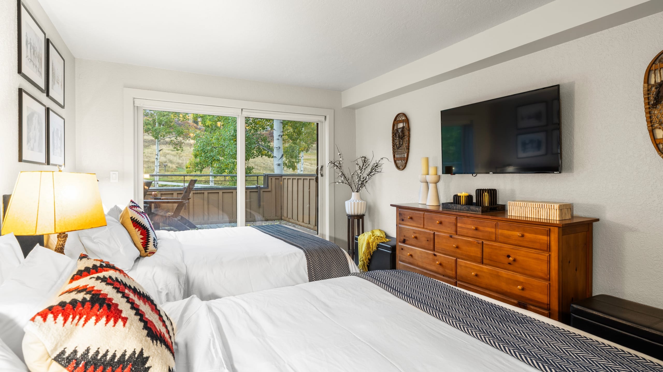 The bedroom features 2 queen beds, TV, deck access and an ensuite bathroom.