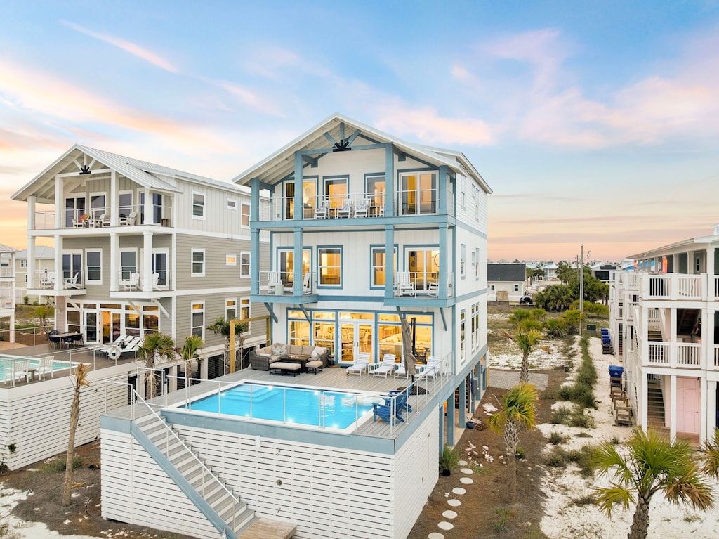 Modern coastal architecture features multiple balconies and a rooftop pool, set in a quiet beachside neighborhood at golden hour.