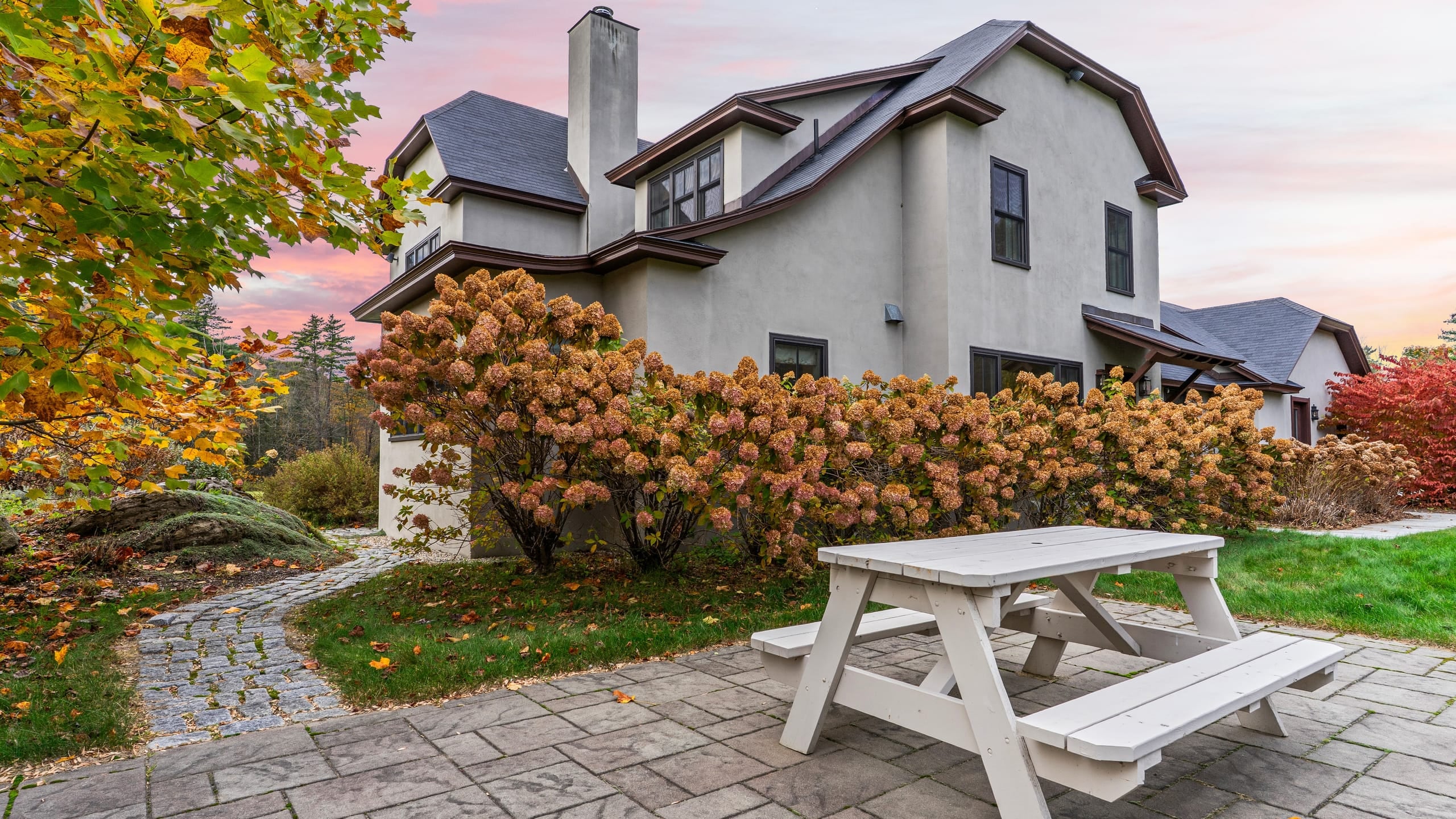 Exterior of home with stone patio and picnic table.