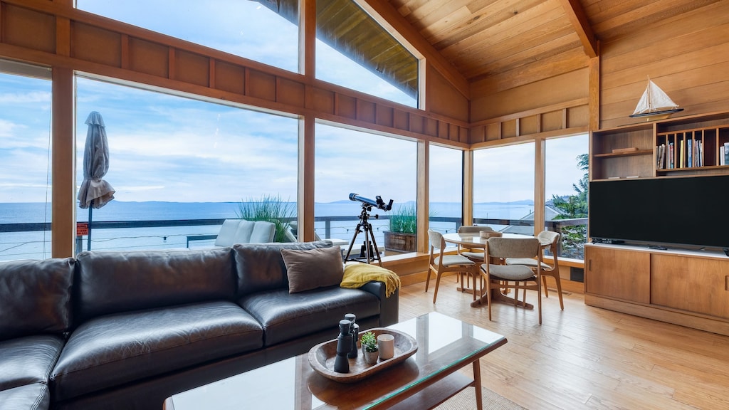 Bright living room with a TV, floor-to-ceiling windows, and ocean view.