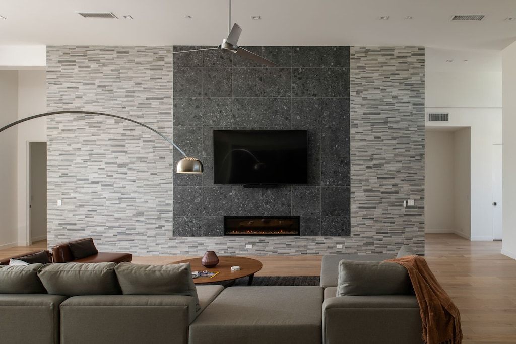 The stunning great room centers on a floor-to-ceiling stone fireplace wall, a large smart TV, and comfortable sectional seating.