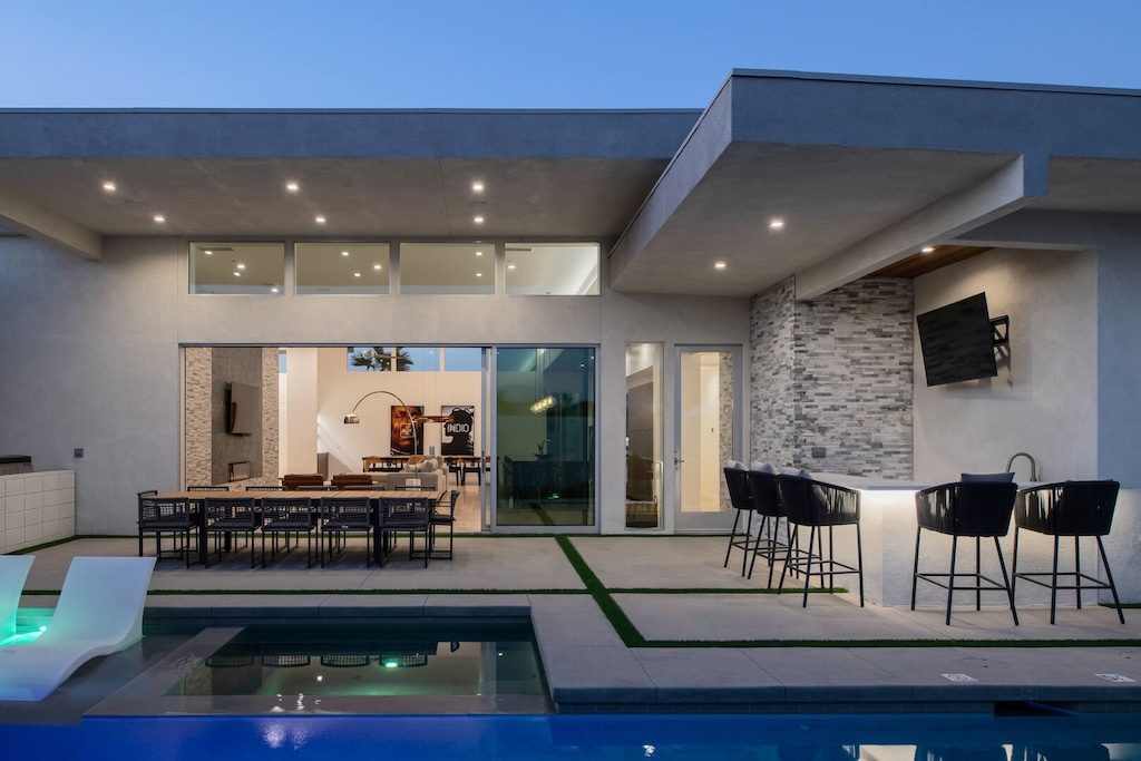 The ultimate evening entertaining space: A full outdoor wet bar with TV, covered dining area, and the sparkling pool with spa lighting.