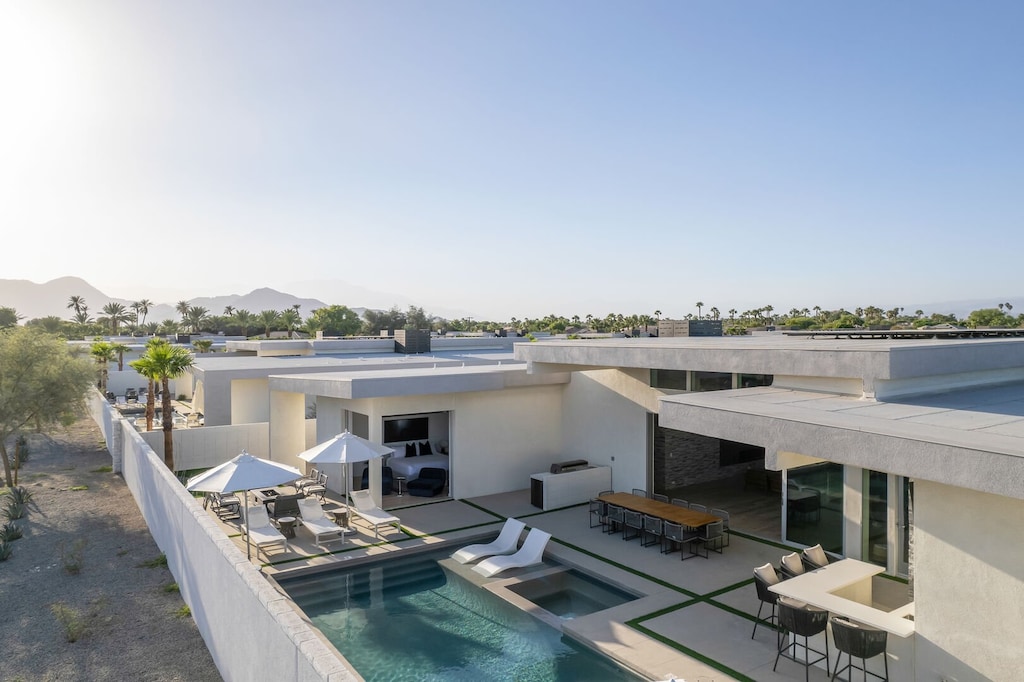 An elevated view showcasing the fully private backyard, pool, dining, and unobstructed mountain views on a clear day.