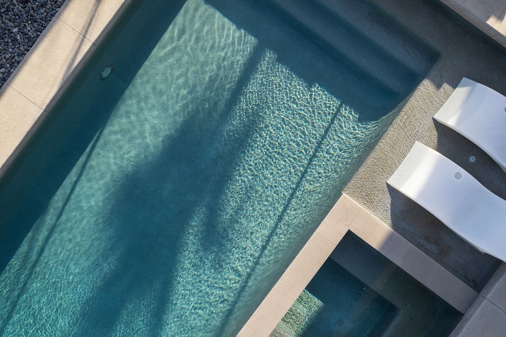 A refreshing overhead view of the sparkling pool and submerged loungers, highlighting the clean lines of the adjacent hot tub.