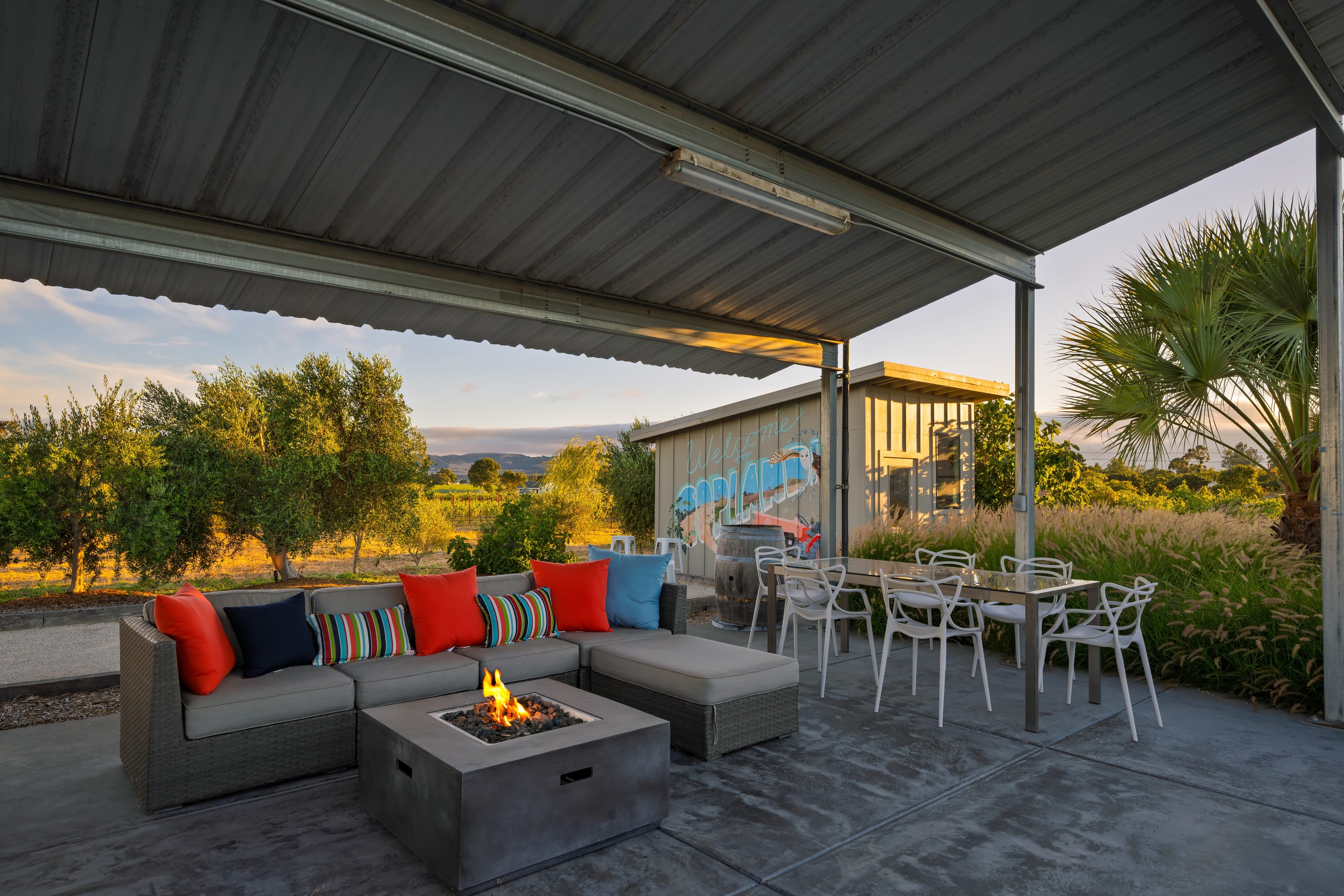 Cozy covered lounge and dining area with a modern fire pit and vineyard views.
