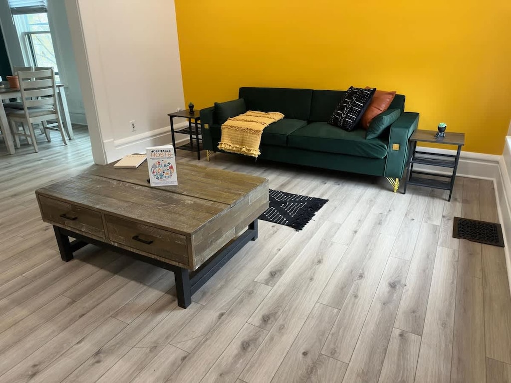 "& Unwind in style in our modern Jungle House living room in Columbus! Our vibrant orange tufted sofa, cozy yellow throw blanket, and chic cowhide rug create the perfect space to relax. & Our plants are looking forward to hosting you soon  Book y