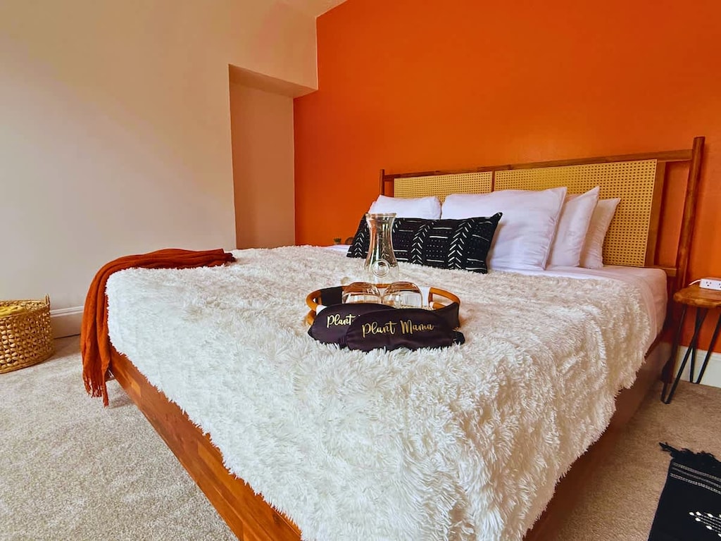 "& Experience comfort and elegance in our cozy Jungle House bedroom in Columbus! Our plush bed with soft pillows, a warm white blanket, and stylish black decorative pillows promises you a restful night's sleep. & Our plants are looking forward to hos