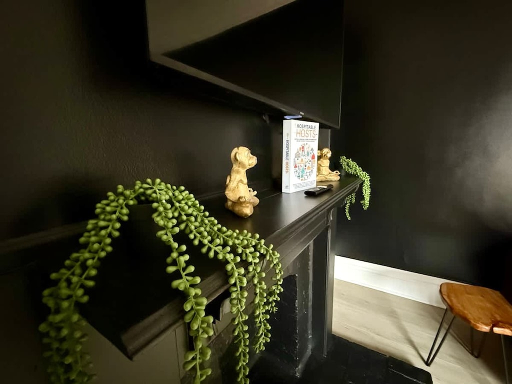 Host memorable gatherings in our stylish dining area at Jungle House Airbnb, featuring a sleek wooden table, vibrant yellow chairs, and a lush green accent wall  The perfect blend of modern elegance and cozy charm in Short North Columbus