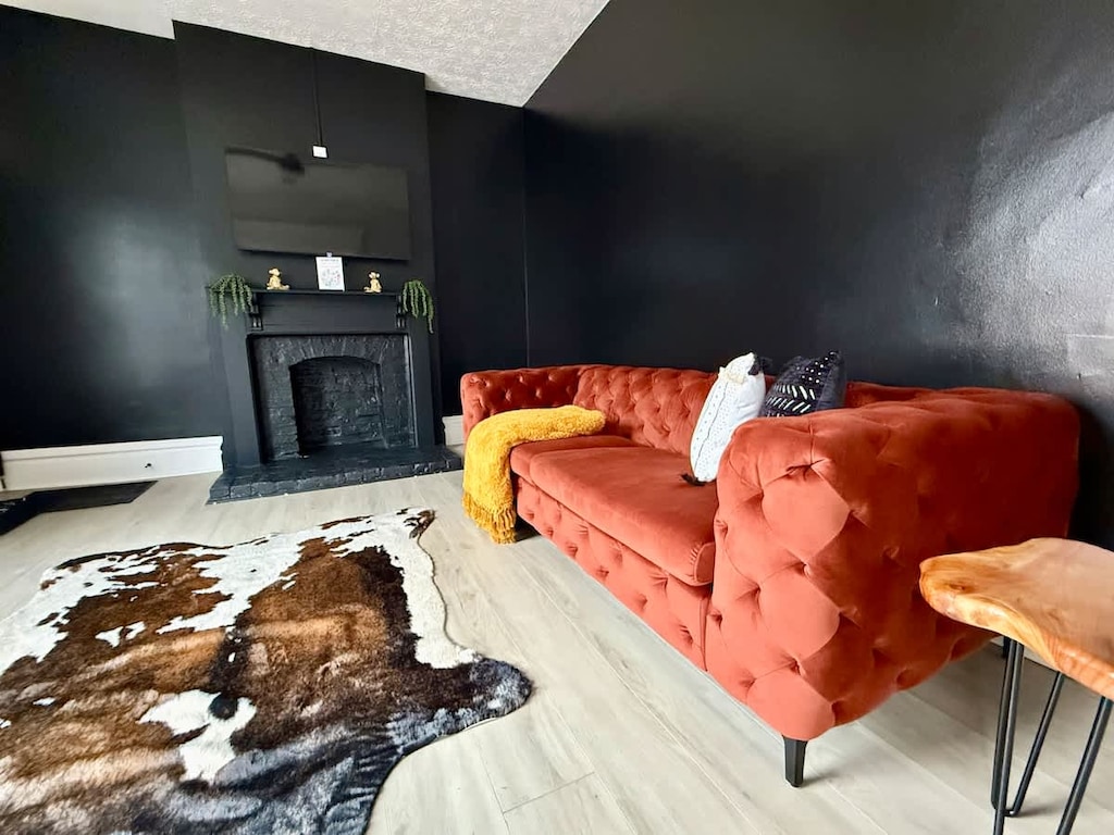 "& Unwind in style in our modern Jungle House living room in Columbus! Our vibrant orange tufted sofa, cozy yellow throw blanket, and chic cowhide rug create the perfect space to relax. & Our plants are looking forward to hosting you soon  Book y