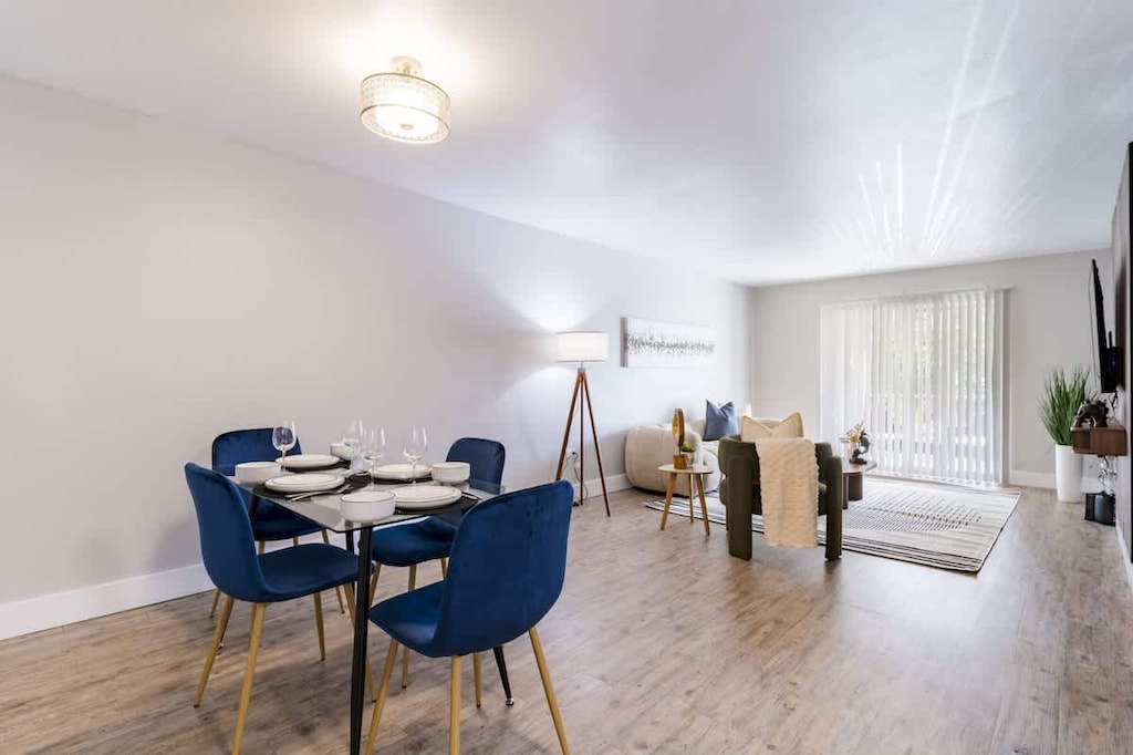 An open-concept dining and living area featuring rich blue velvet chairs, warm wood floors and bright atmosphere