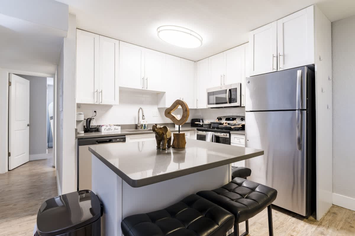 Fully equipped kitchen featuring stainless steel fridge, microwave and dishwasher, complemented by a large island with seating for two