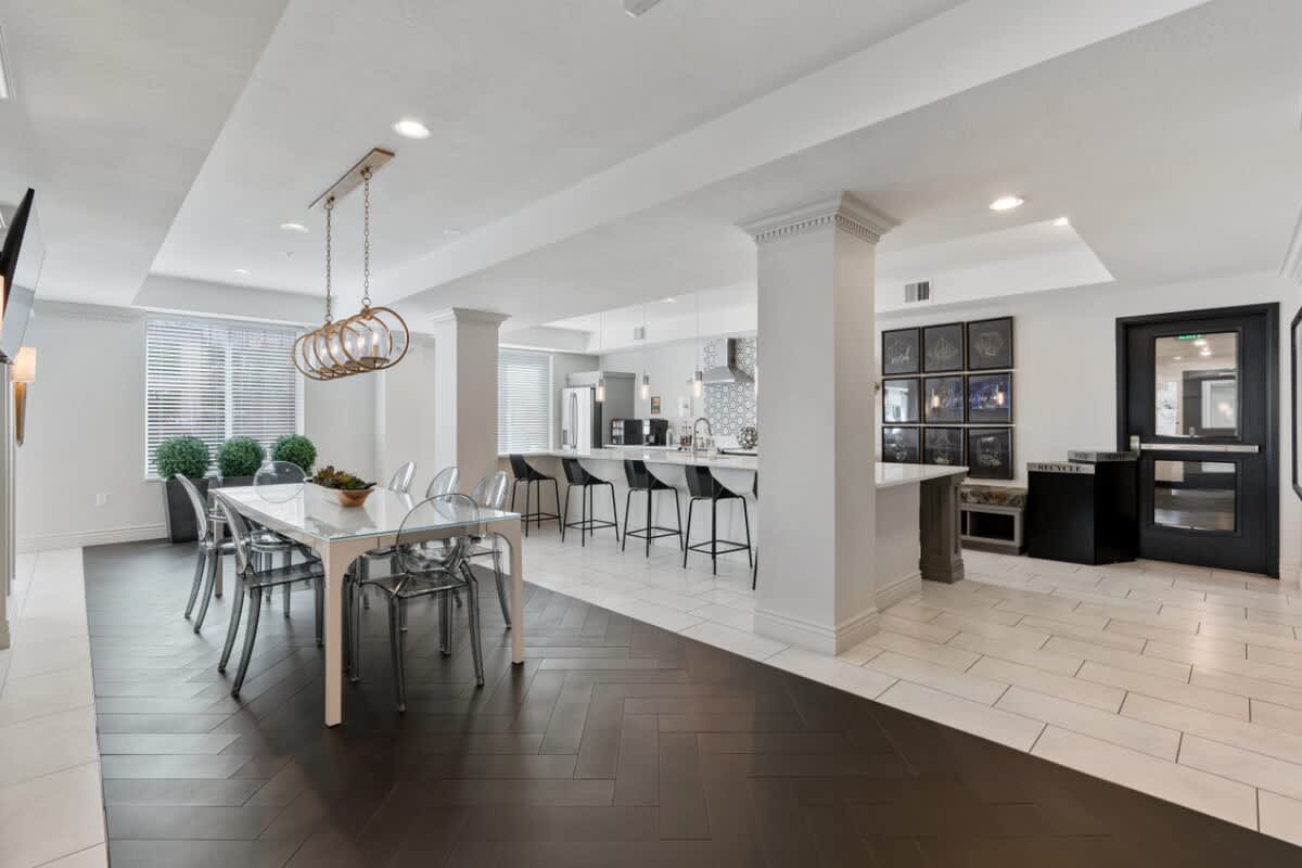 Our social dining room offers a perfect blend of comfort and style, with a chandelier, TV, and lush plants.