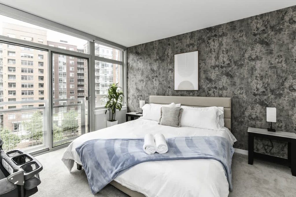 Bright, modern bedroom 1 featuring a king-size bed, pack n play crib and large windows that let in plenty of natural light.