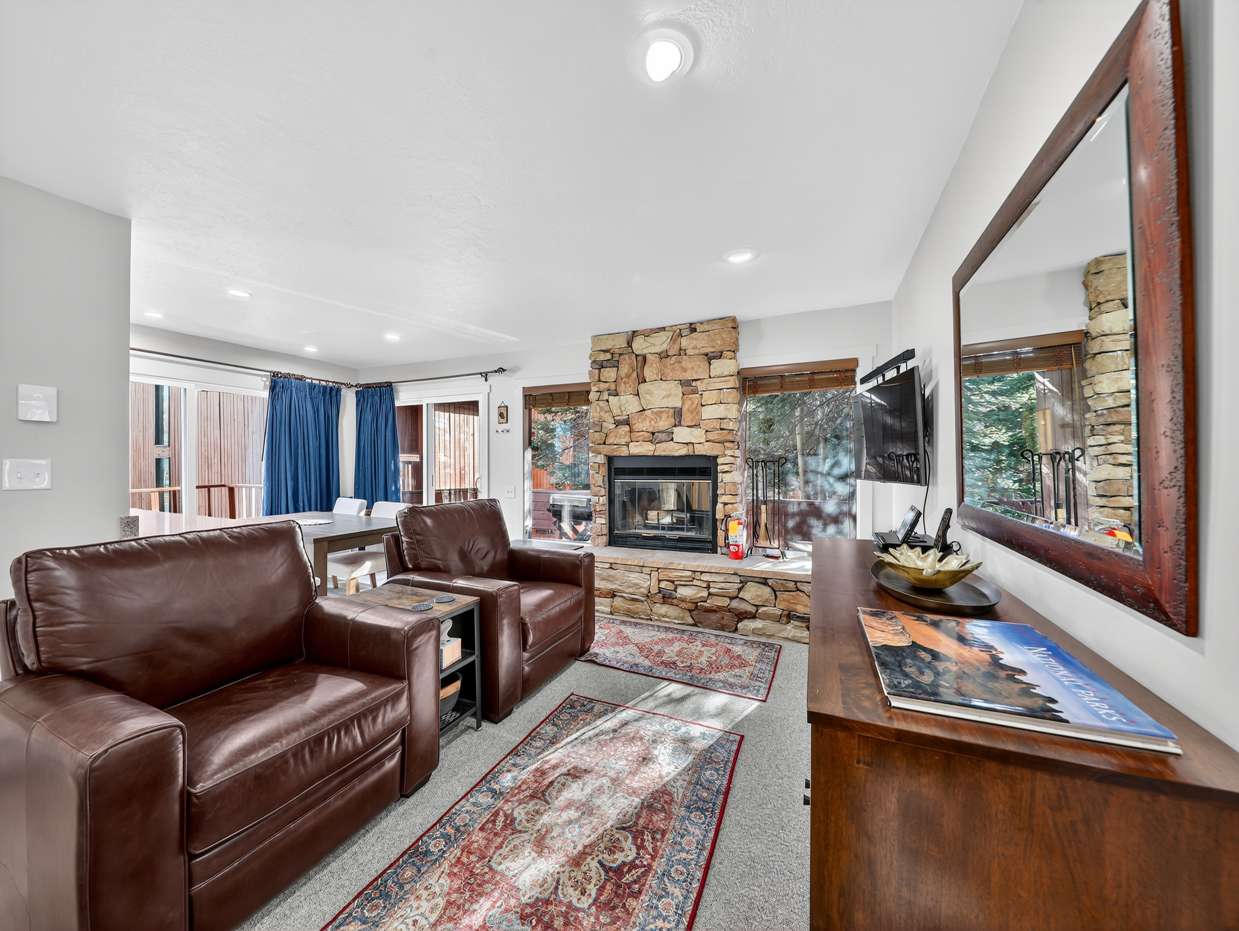 Unwind in your spacious living room where rich leather seating faces a stunning stone fireplace. Watch the flames dance while you relax on comfortable sofas, enjoying mountain views through expansive windows.