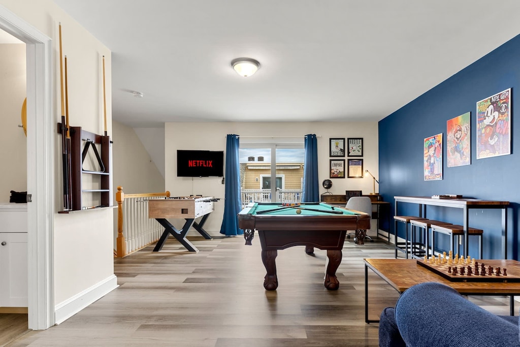 "The Game Room" features foosball, pool, wall-mounted connect 4, checkers, chess, dominoes, tic-tac-toe, a bar table with 3 stools, wall-mounted TV, slider leading to private balcony and a “work-from-home” desk