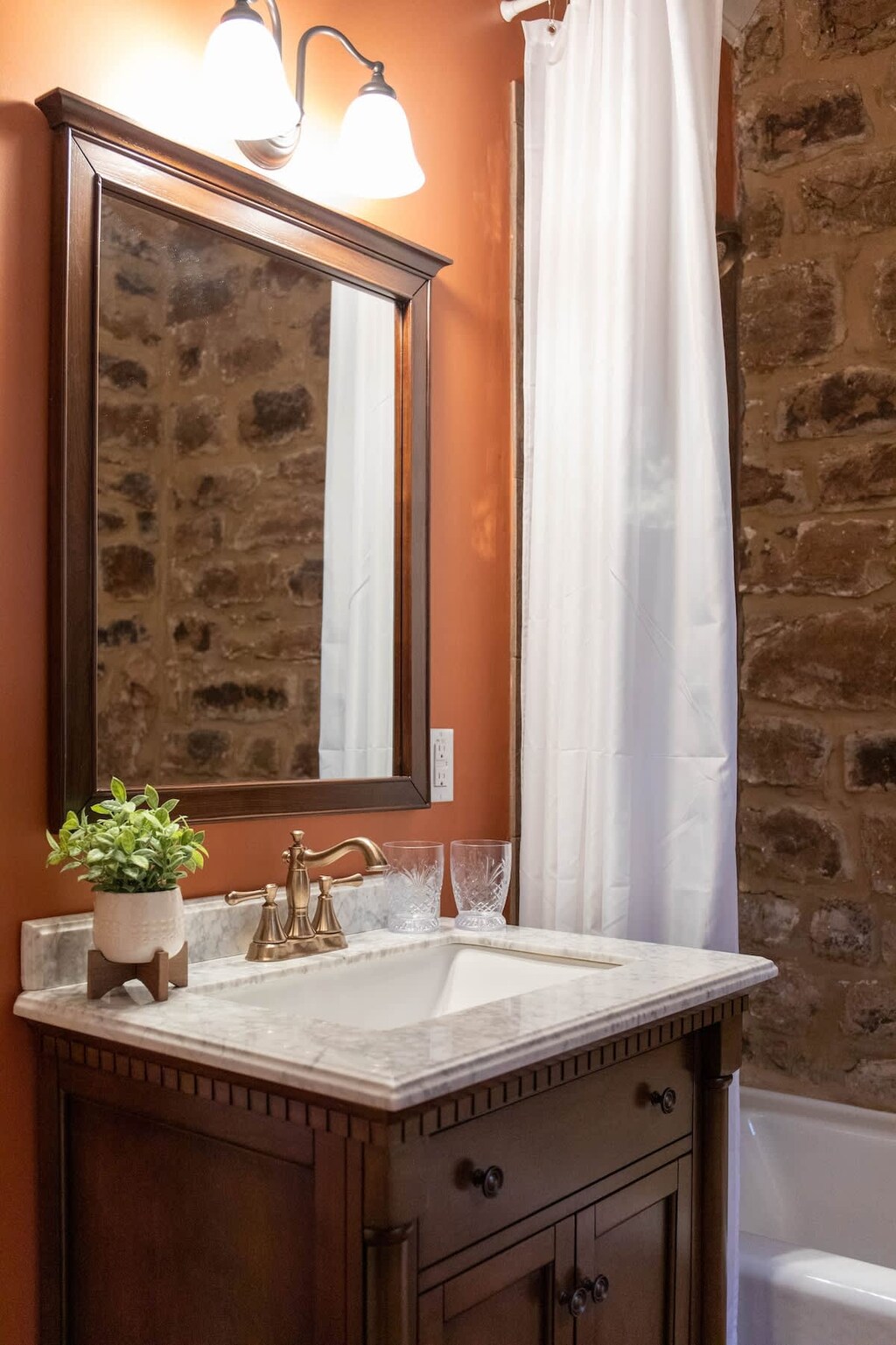 Modern amenities blends with native stone and historic windows to bring a cozy warmth to this bathroom.