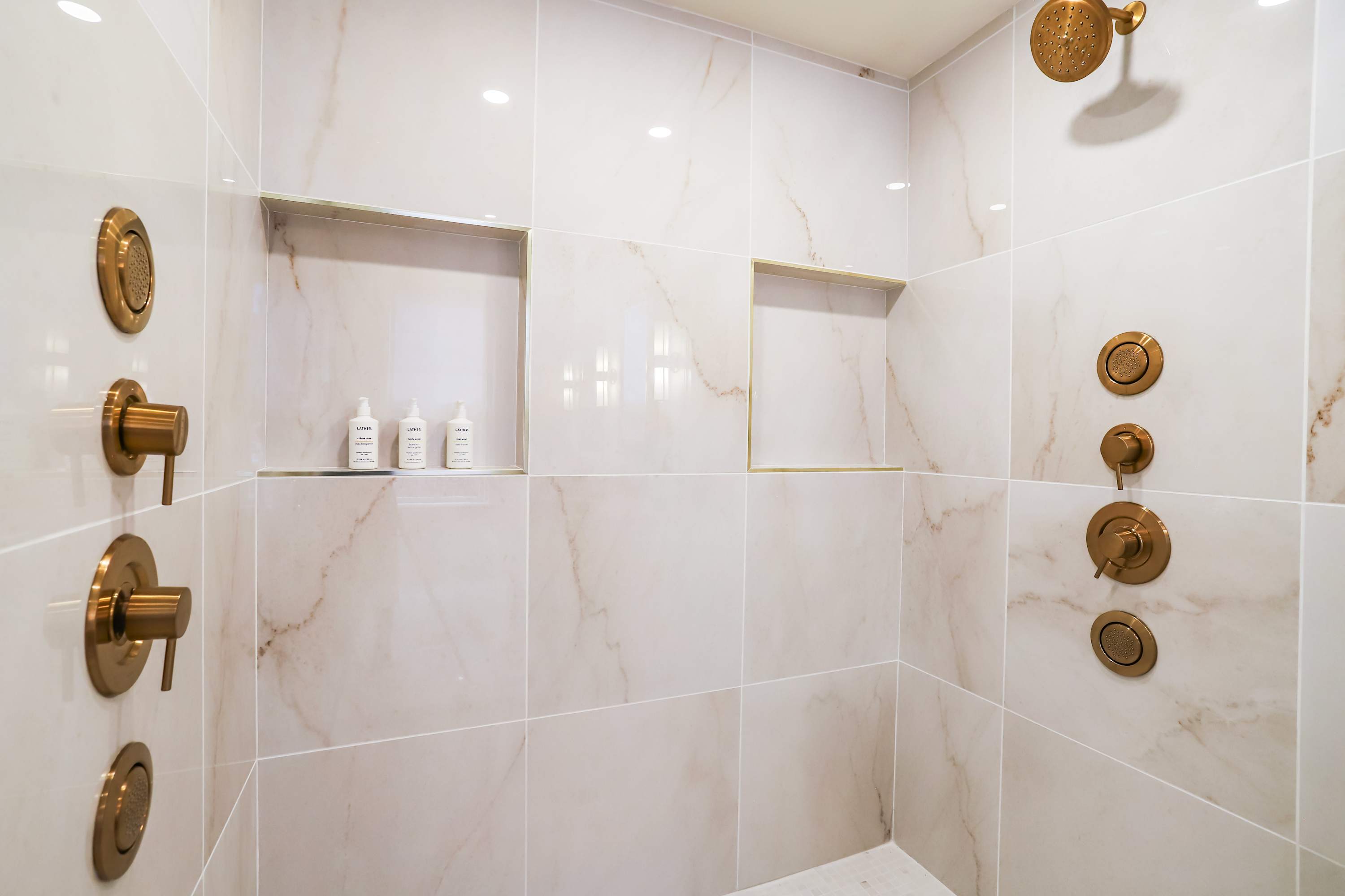 Tiled shower with gold fixtures and built in shelving. Tiled shower with gold fixtures and built in shelving.