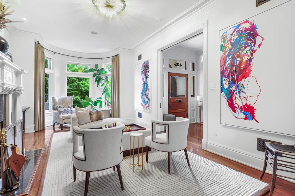 Front living room on the main floor with bay windows, seating area, art, and a decorative firelace. 
