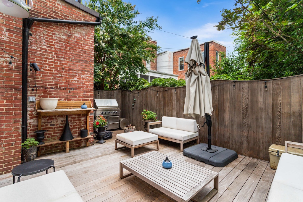 Backyard with outdoor furniture including a sun umbrella, plants, and a grill. 