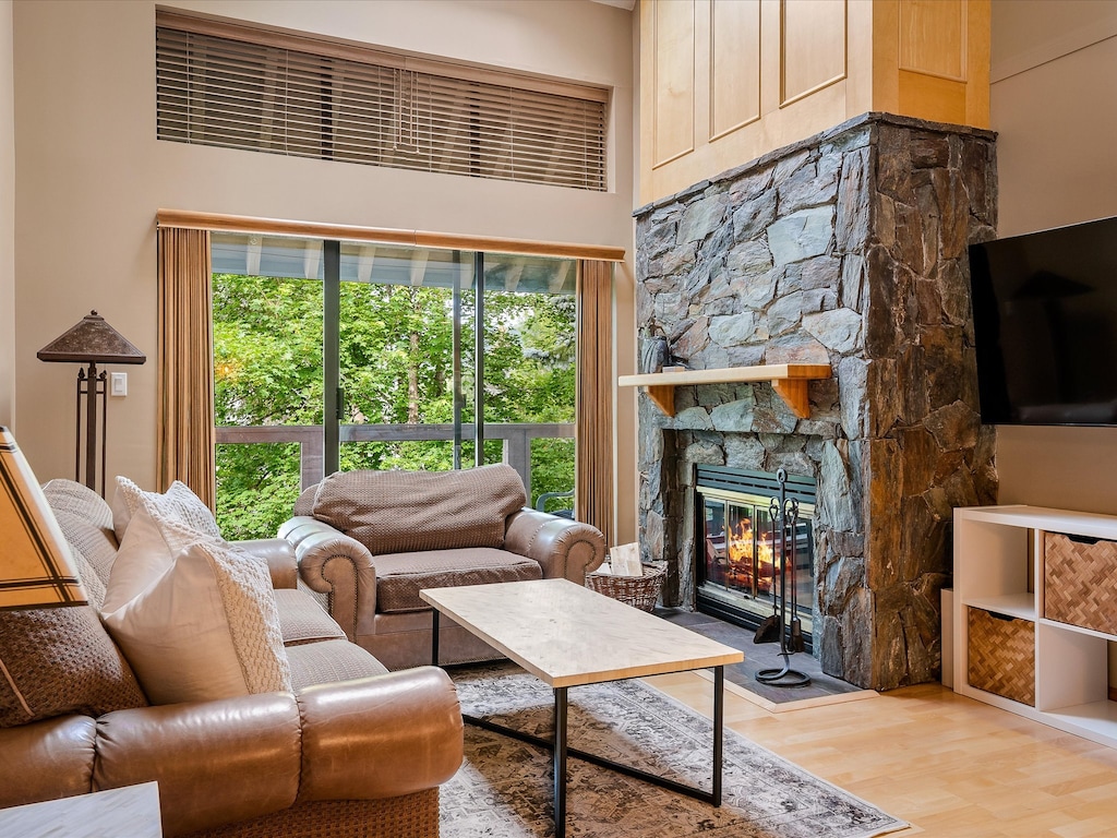 Living Room - Large couch and chaise, cozy real wood fireplace, 65" SmartTV with cable channels, sliding doors leading onto spacious patio.