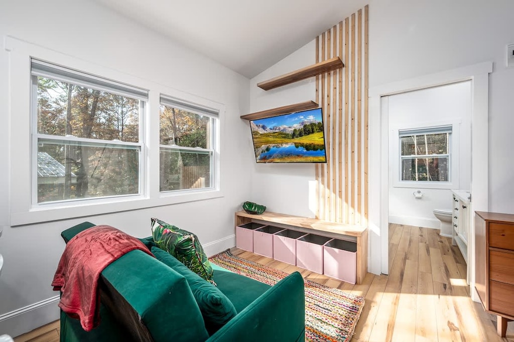 Cozy up in this bright bloom nook — complete with a plush green loveseat, smart TV, and plenty of natural light for laid-back lounging. 