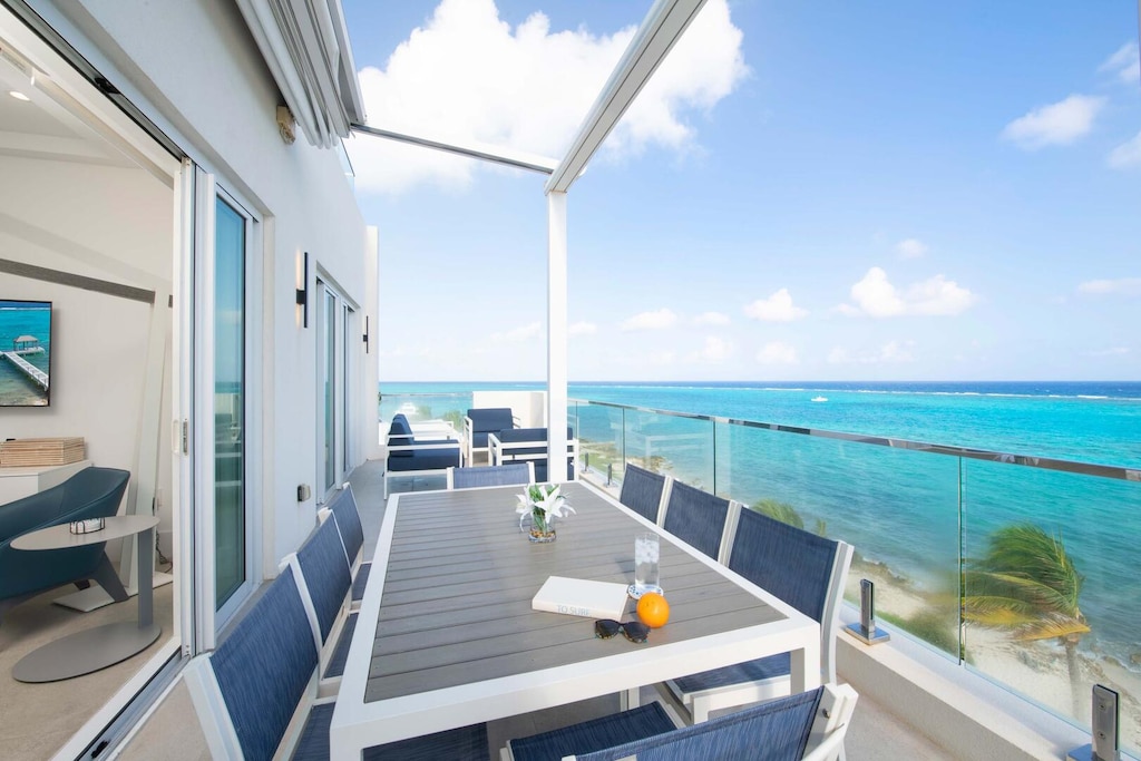 Sprawling furnished balcony with lounge seating and outdoor dining table.